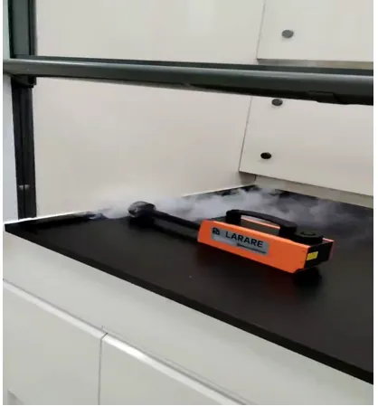 Arc-shaped fume hood containment test with orange smoke generator emitting vapor on black worktop
