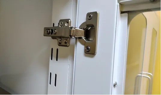 Close-up of adjustable nickel-plated hinge on white all-steel laboratory bench cabinet door