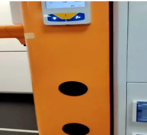 Close-up detail of an orange arc-shaped fume hood column with circular access ports and control panel