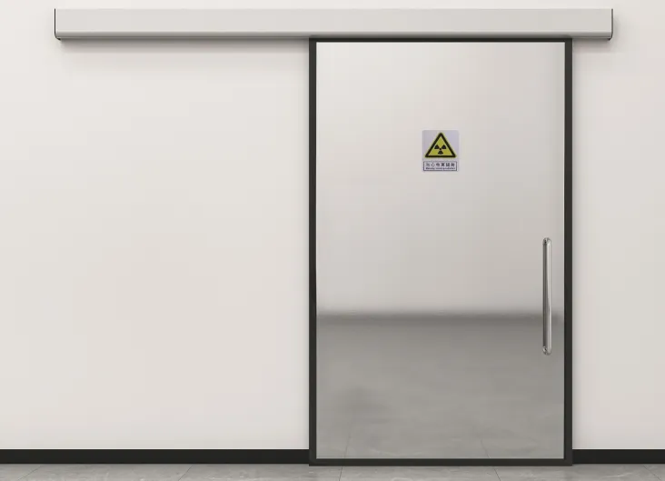 Installed radiation-protective automatic sliding lead door with silver panel, black frame, and trefoil warning sign