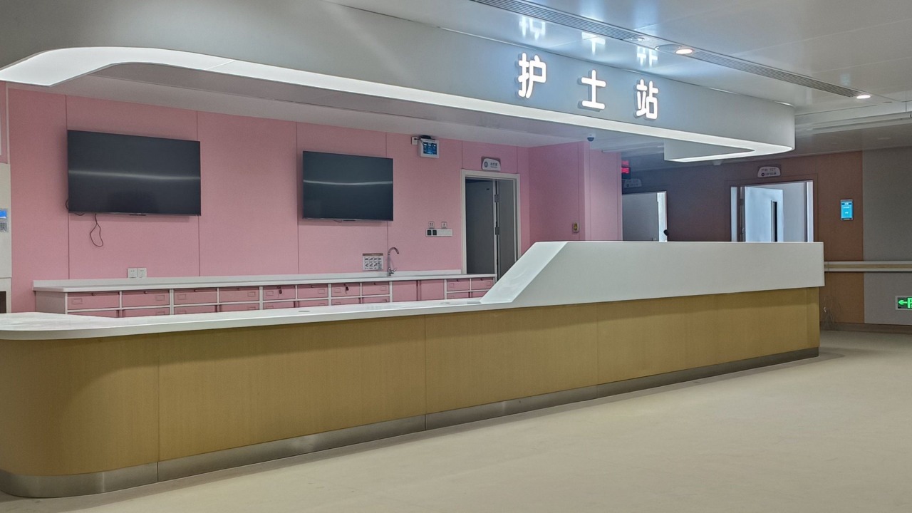 Estación de enfermería moderna de hospital con un mostrador de recepción curvo blanco y de madera, pared de almacenamiento rosa y letrero iluminado de estación de enfermería