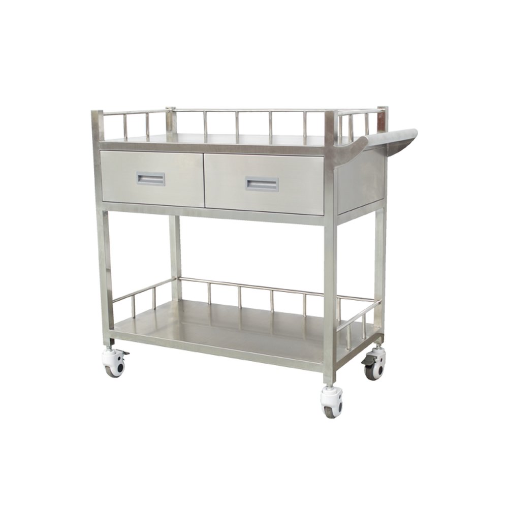 Carro médico móvil de acero inoxidable cepillado sobre un fondo blanco liso y uniforme, visto desde un ligero ángulo frontal de tres cuartos. Tiene dos estantes de almacenamiento planos y fáciles de limpiar, bordeados con barandillas de seguridad metálicas verticales bajas, dos cajones anchos uno junto al otro entre los niveles, cada uno con un tirador rectangular gris empotrado, un asa curva de empuje en la parte superior derecha y cuatro ruedas giratorias bloqueables con carcasas blancas y bandas de rodadura de goma gris, diseñado para entornos clínicos para transportar suministros médicos.