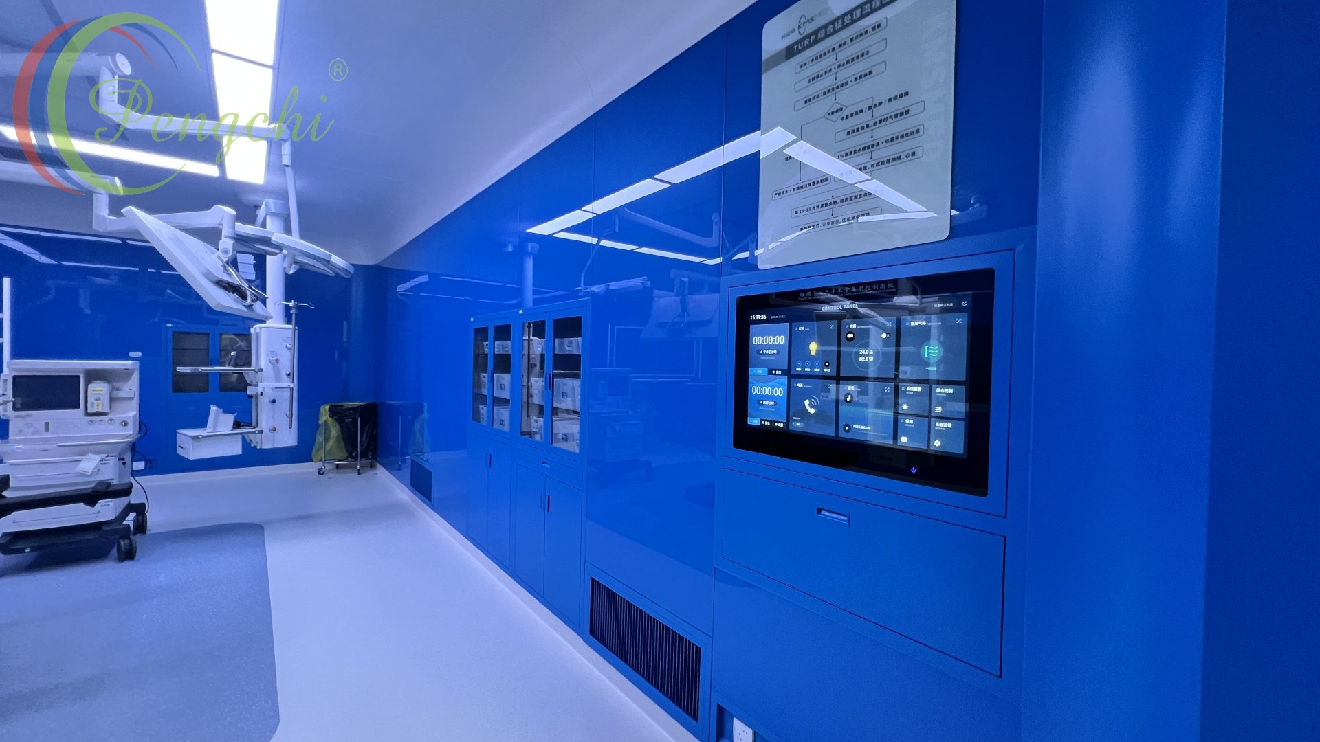 ห้องผ่าตัดที่ว่างเปล่าพร้อมผนังสีน้ำเงินเข้มเงางาม พื้นสีขาว และแสงไฟ LED ที่สว่างสดใส หน้าจอสัมผัสที่ติดตั้งฝังผนังทางด้านขวาแสดงตัวจับเวลาและระบบควบคุมห้องใต้แผนผังขั้นตอนภาษาจีน ตู้กระจกสีน้ำเงินตั้งเรียงรายตามแนวผนัง ขณะที่ไฟผ่าตัดสีขาวและรถเข็นการแพทย์ตั้งอยู่ทางด้านซ้าย การสะท้อนบนแผงเงางามช่วยเน้นย้ำถึงบรรยากาศทางคลินิกที่สะอาดและเต็มไปด้วยเทคโนโลยีชั้นสูง
