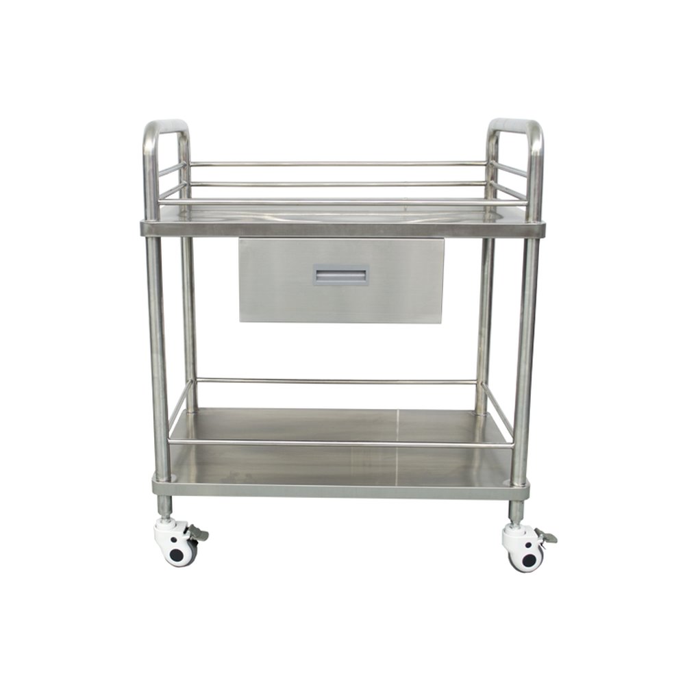 Carro médico de dos niveles de acero inoxidable pulido, mostrado de frente y parcialmente recortado sobre un fondo de estudio blanco liso. El estante superior tiene barandillas tubulares laterales y traseras para evitar que los objetos se deslicen, con un cajón central de acero inoxidable cepillado y un tirador empotrado gris montado debajo. Un estante inferior de acero inoxidable a juego tiene barandillas perimetrales bajas, sostenido por cuatro gruesas patas verticales de tubo metálico pulido. Ruedas giratorias blancas con bloqueo, parcialmente visibles, con pestañas de freno grises se sitúan en las esquinas, iluminadas por una iluminación de estudio uniforme que proyecta reflejos suaves y sutiles sobre las superficies metálicas lisas.