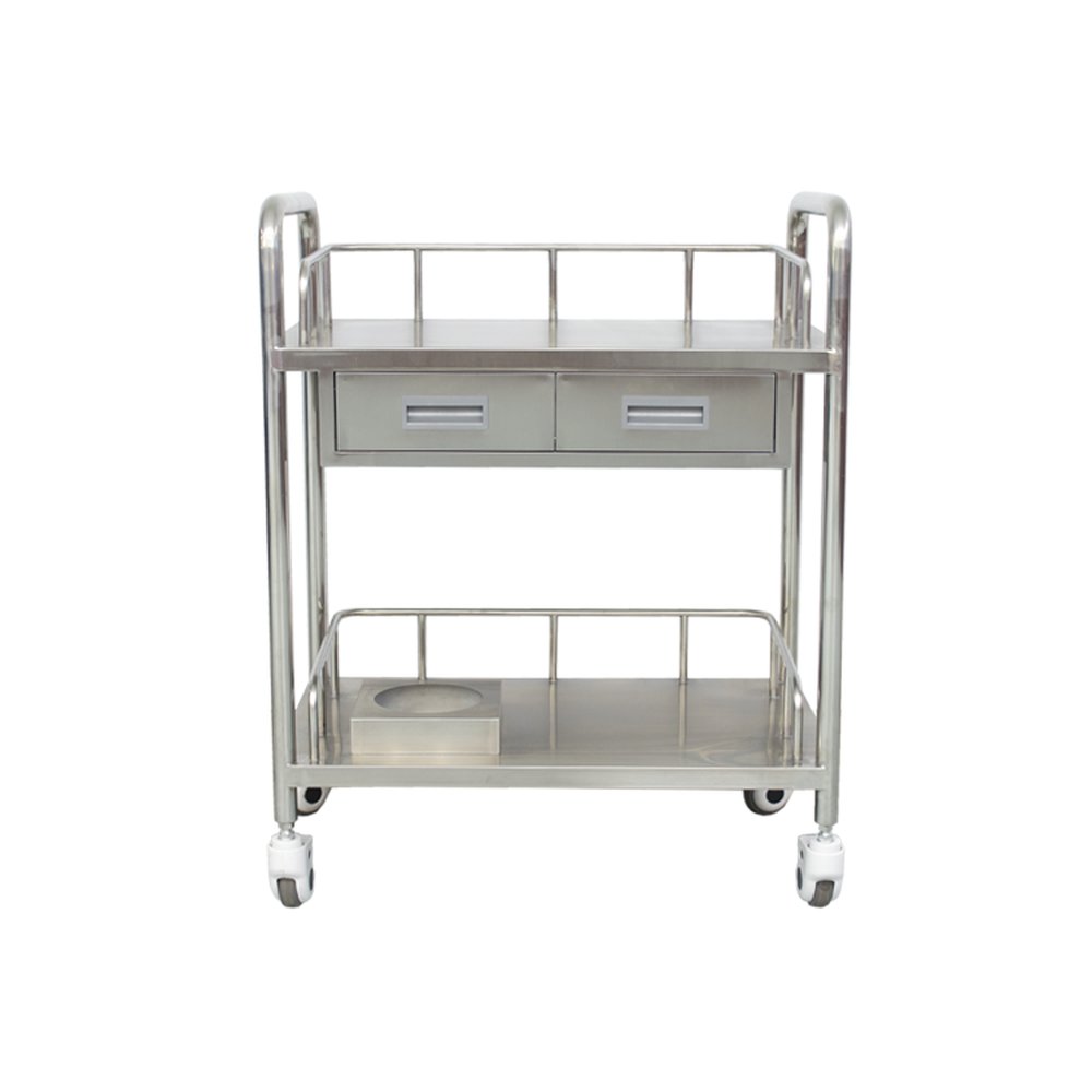 Carrito utilitario médico de acero inoxidable pulido aparece de frente contra un fondo de estudio blanco liso, con dos estantes planos de almacenamiento escalonados bordeados por barandillas de seguridad metálicas bajas y curvas. Dos cajones uno junto al otro con tiradores rectangulares grises empotrados se sitúan debajo del estante superior, mientras que un bloque metálico cuadrado elevado con un recorte circular para una palangana descansa sobre el lado izquierdo del estante inferior. Cuatro postes cilíndricos pulidos forman la estructura, que soporta cuatro ruedas giratorias con soportes blancos, bujes blancos y banda de rodadura de goma negra, con una iluminación brillante y uniforme que proyecta suaves reflejos sobre las superficies metálicas lisas.
